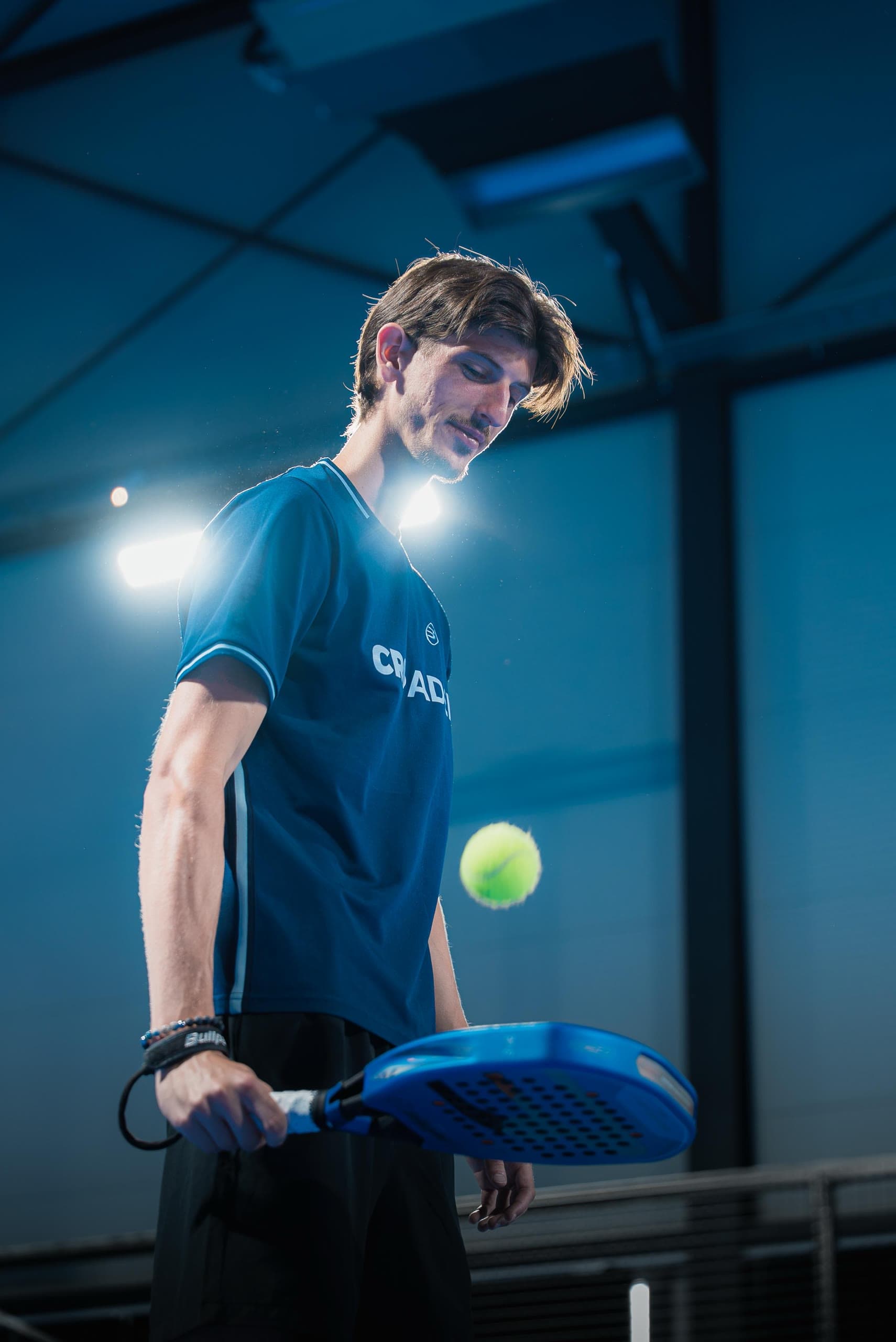 Ahmed Musić s plavim reketom i žutom loptom na padel terenu